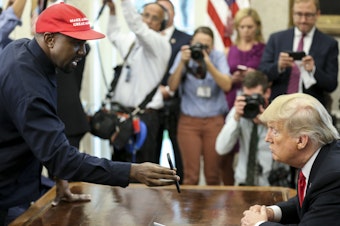 caption: Rapper Kanye West shows a picture of a plane on a phone to President Trump during a meeting in the Oval Office on Thursday.