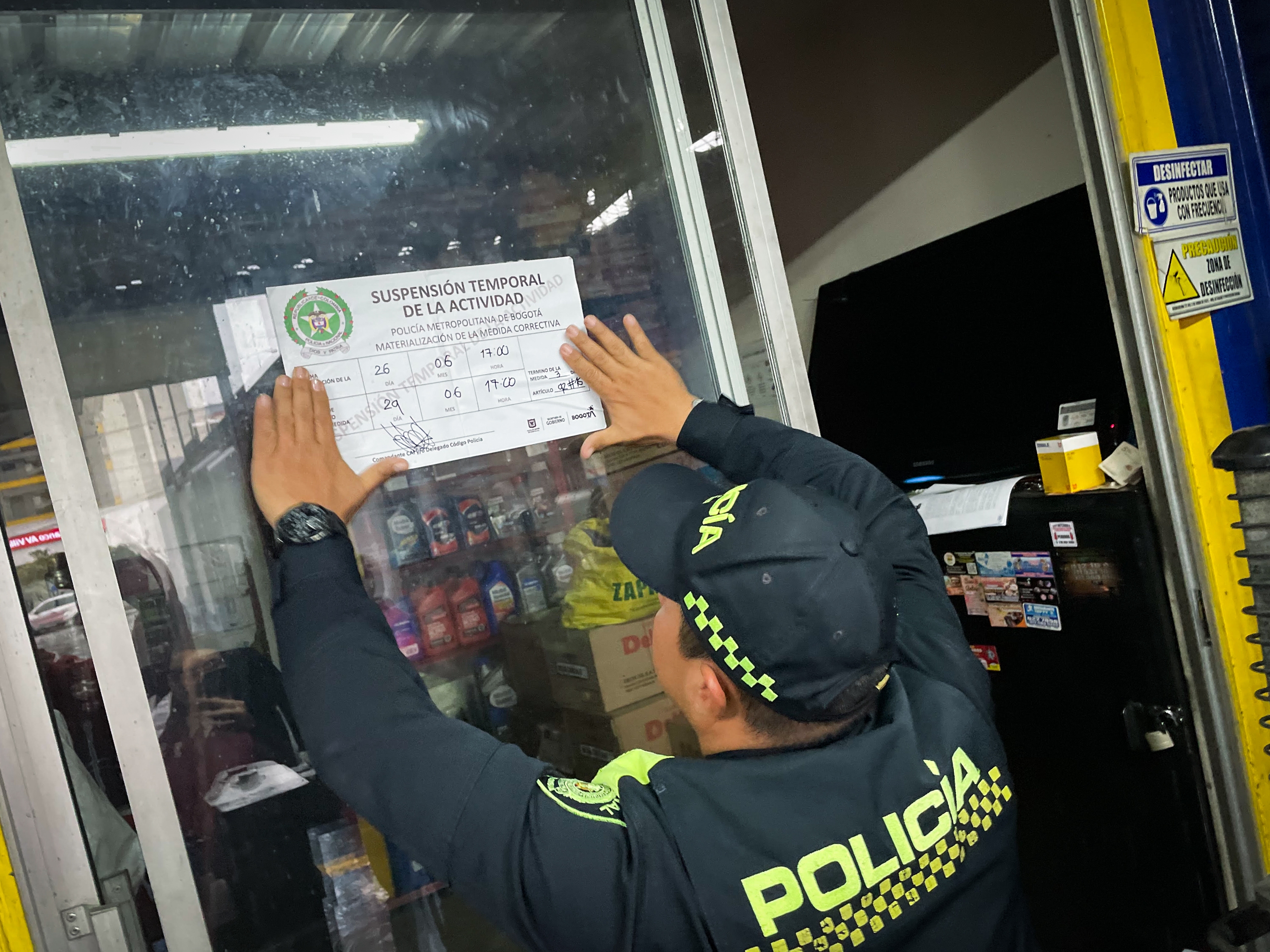 caption: A police officer temporarily shuts down an auto services shop in Bogotá, Colombia, June 26, saying his business permit and other paperwork were out of date. Authorities are targeting tire-repair shops that motorists have flagged for their suspected collaboration with <em>pinchallantas</em>, or tire-puncturers.