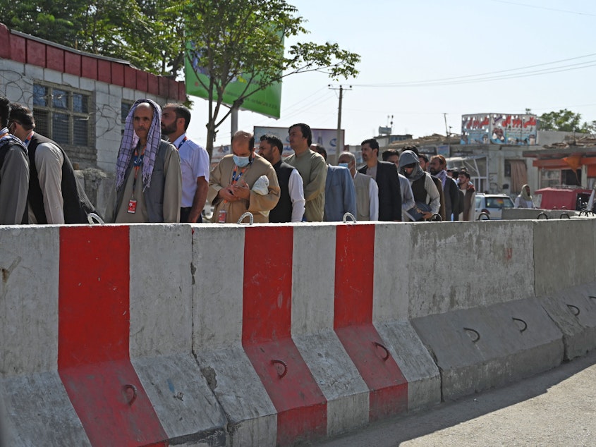 caption: Airport workers stand in a queue at a check point before entering the Kabul International Airport in Kabul on Sept. 4.