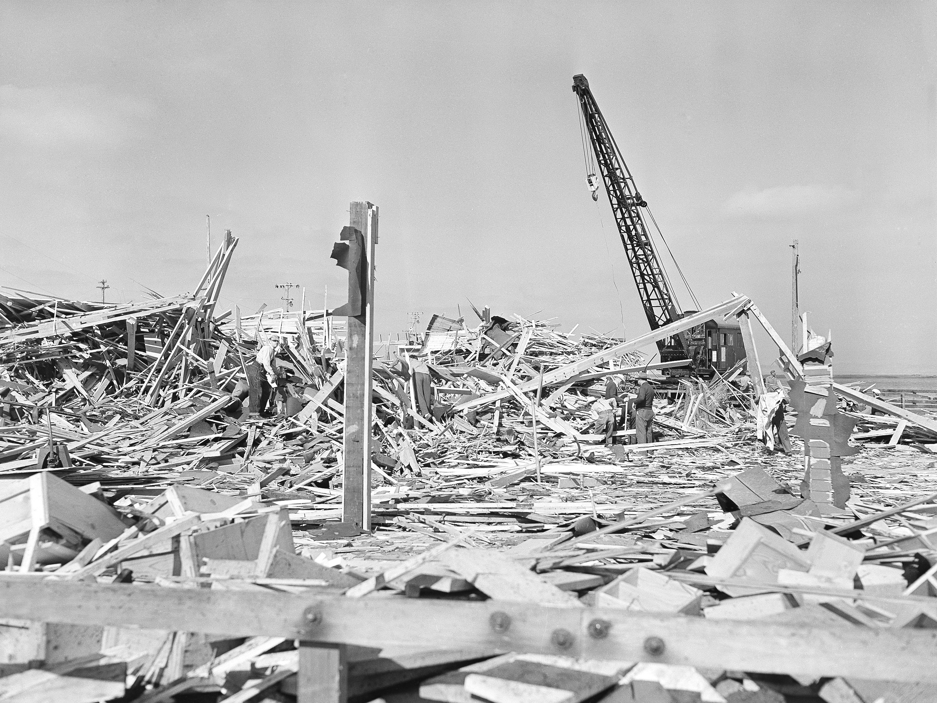 caption: Workmen searched through the debris of what was the carpenter shop on the pier at Port  in Chicago, Calif. on July 18, 1944, after the building was leveled by the explosion of two munition ships the evening of July 17. Other buildings on the waterfront and in the town itself were shattered by the terrific blast, which was felt 50 miles from the scene. 