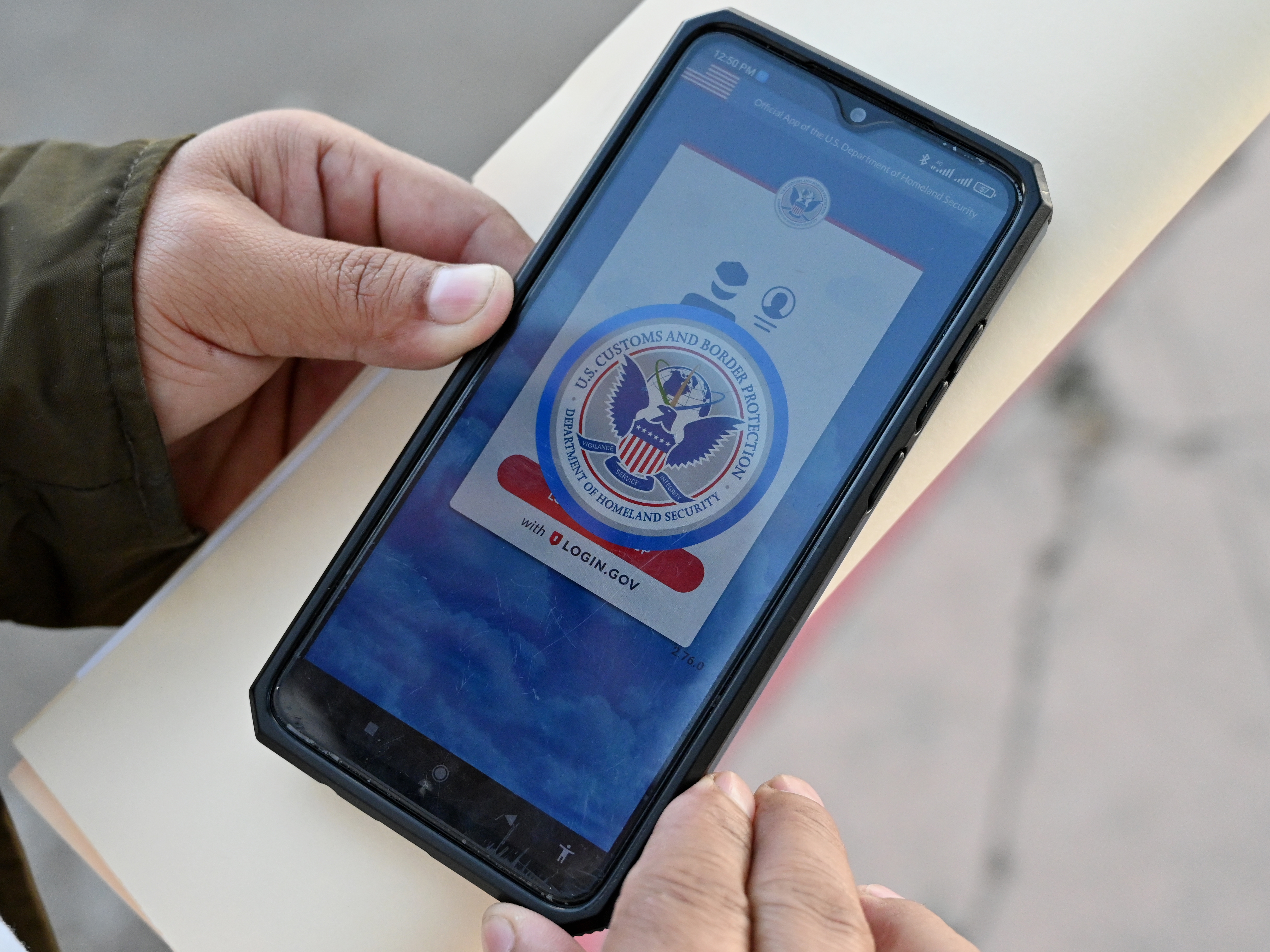 caption: An asylum seeker with a canceled appointment to enter the United States waits to speak to a Mexican immigration official as he reviews the CBP One app at the El Chaparral border crossing port in Tijuana, Mexico, in January 2025.