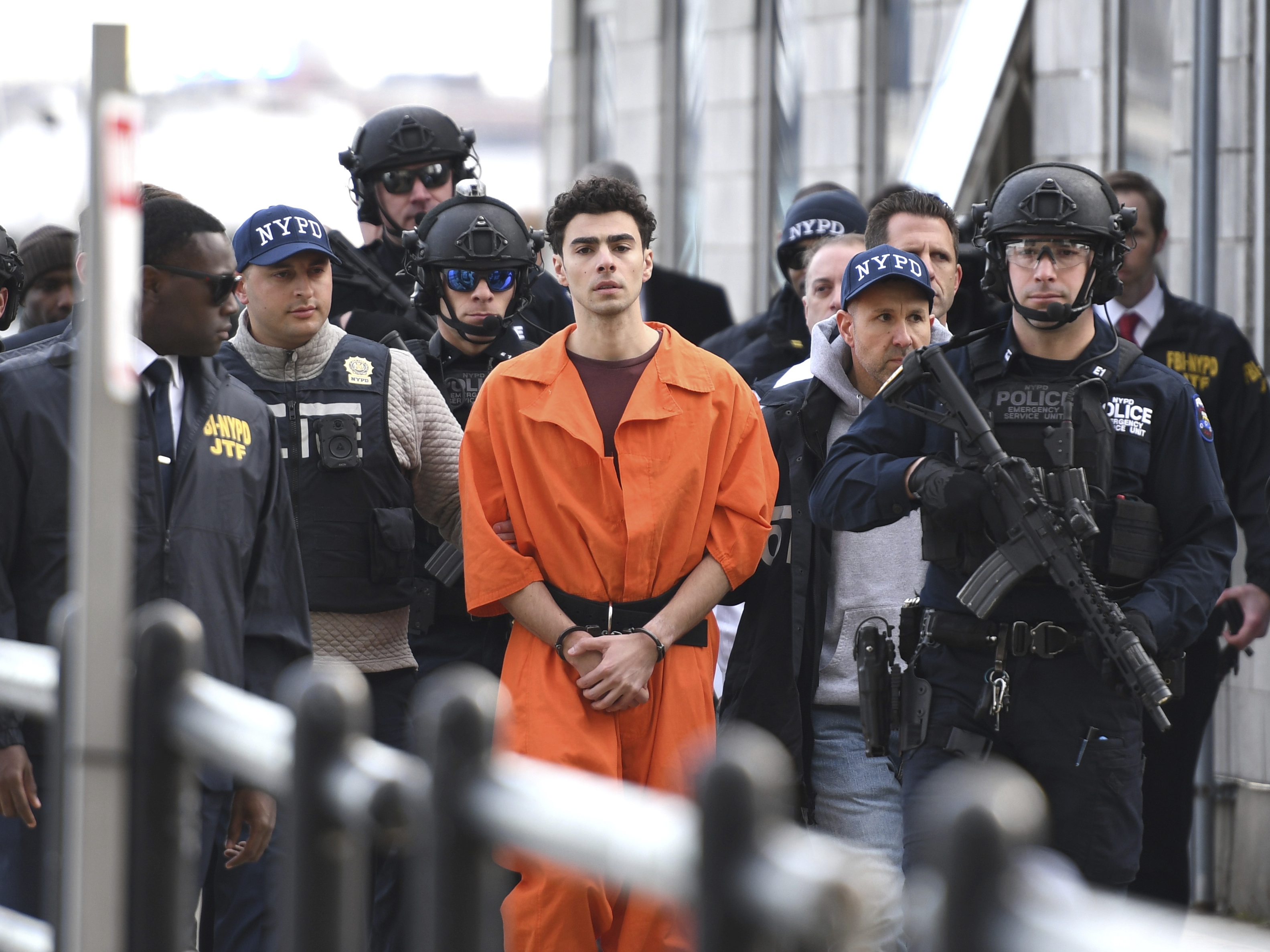 caption: Luigi Mangione, a suspect in the killing of UnitedHealthcare CEO Brian Thompson, is escorted by police from an NYPD helicopter on Thursday, in New York, where he faces four counts of federal charges including murder.