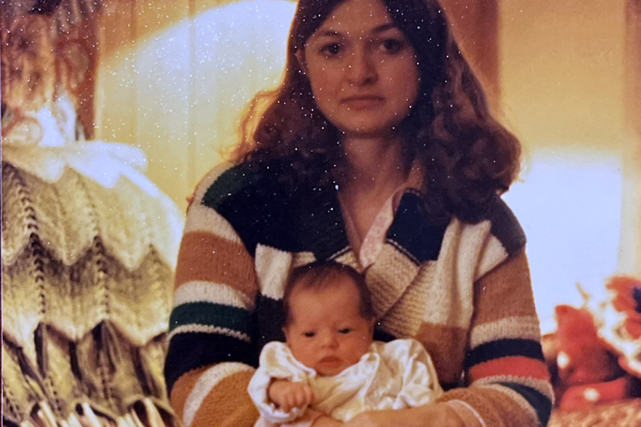 caption: A 25-year-old Elaine Fichter holds her youngest child, Lacy Lahr, in her living room in 1980. 