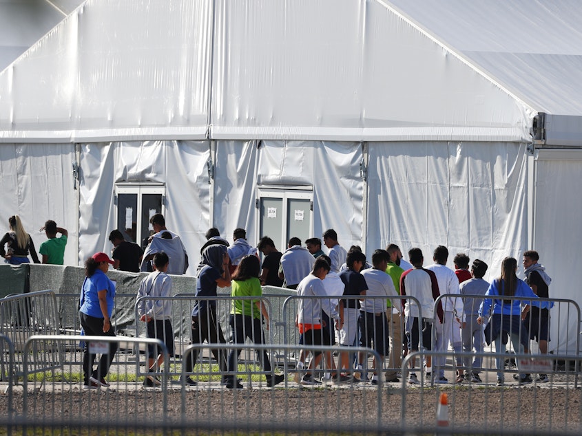 caption: Migrant children line up to enter a tent at the Homestead Temporary Shelter for Unaccompanied Children in Homestead, Fla. in February 2019.