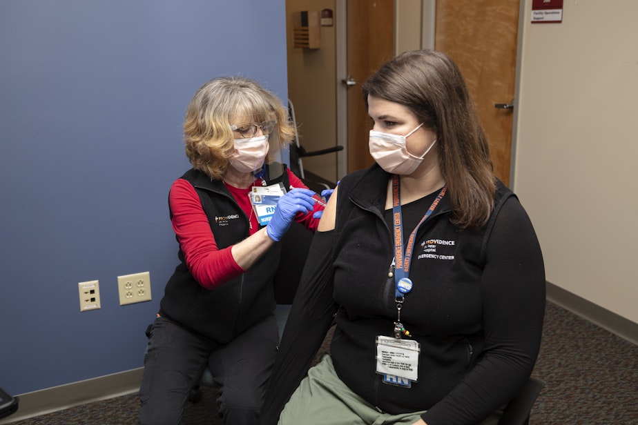 caption: Nurse Elizabeth Vadnais administers the COVID-19 vaccine to fellow nurse Ashlynn Strode of Providence Southwest Washington.