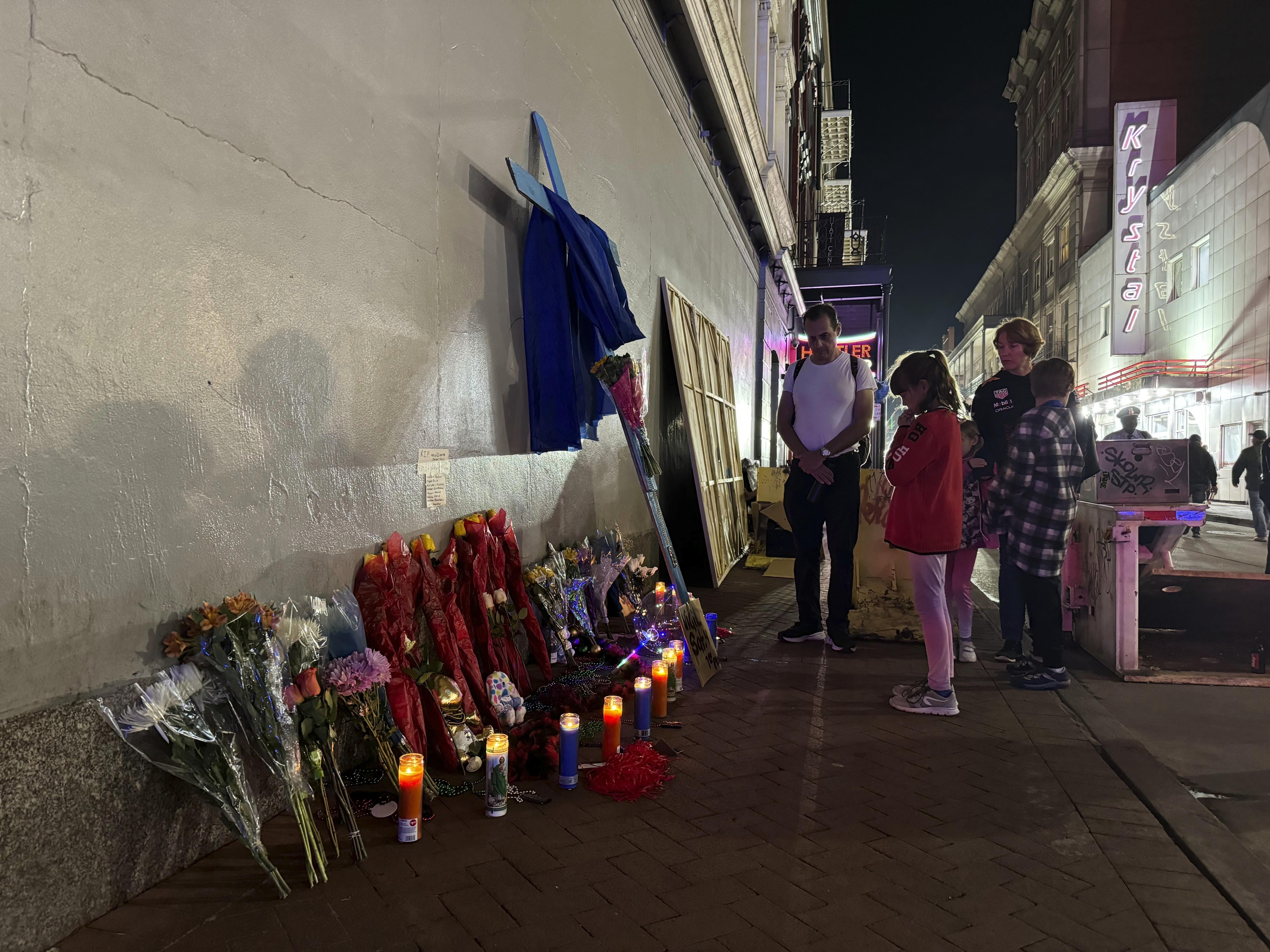 caption: Visitors pay their respects at a memorial to the victims of the deadly attack on Bourbon Street on Thursday after its reopening in New Orleans.
