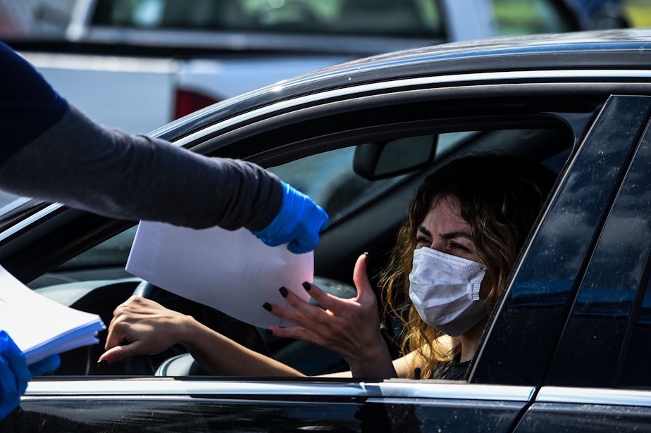 caption: A woman collects unemployment forms at a drive through collection point outside John F. Kennedy Library in Hialeah, Florida, on April 8, 2020. (CHANDAN KHANNA/AFP via Getty Images)