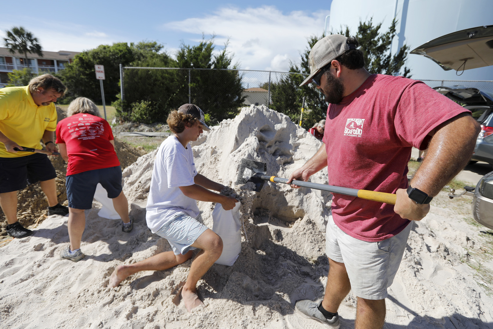 caption: Walker Townsend, at right, from the Isle of Palms, S.C., fills a sand bag while Dalton Trout, in center, holds the bag at the Isle of Palms municipal lot where the city was giving away free sand in preparation for Hurricane Florence at the Isle of Palms S.C., Monday, Sept. 10, 2018. (AP Photo/Mic Smith)