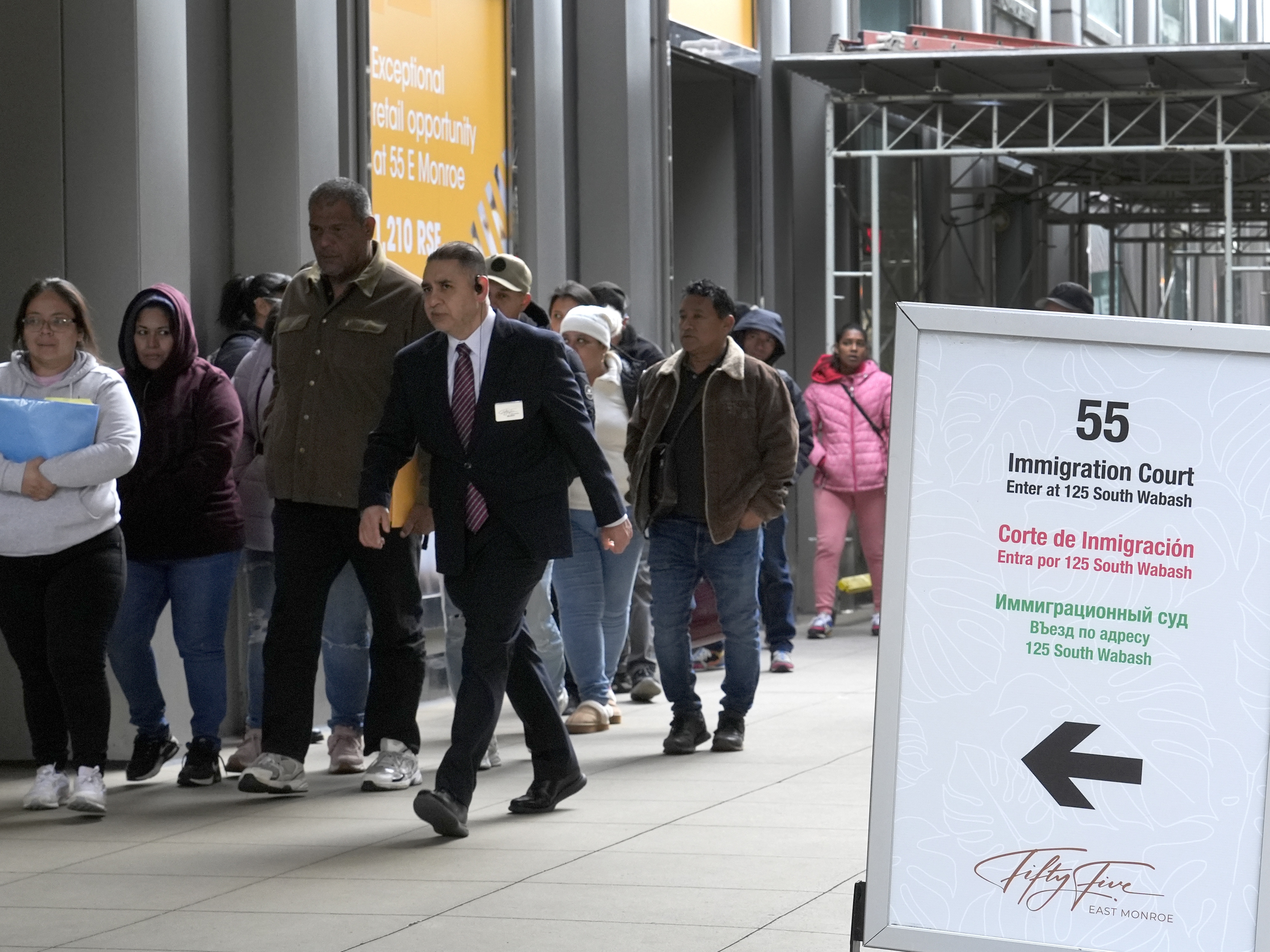 caption: After waiting in a queue, people are led into a downtown Chicago building where an immigration court presides, Nov. 12, 2024.