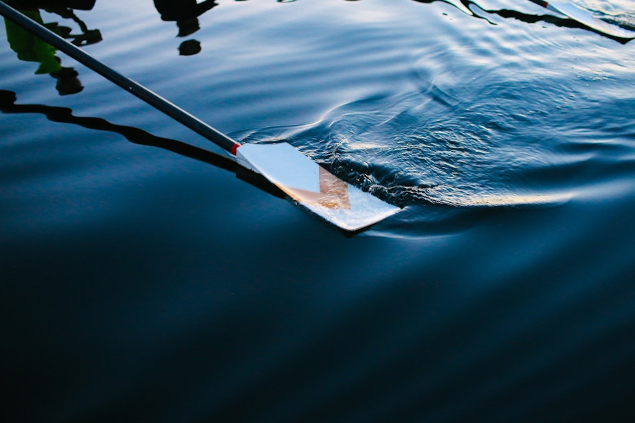 caption: An oar glides along the water as the Pocock Rowing Club women's competitive team trains in the pre-dawn light, September 16, 2021.