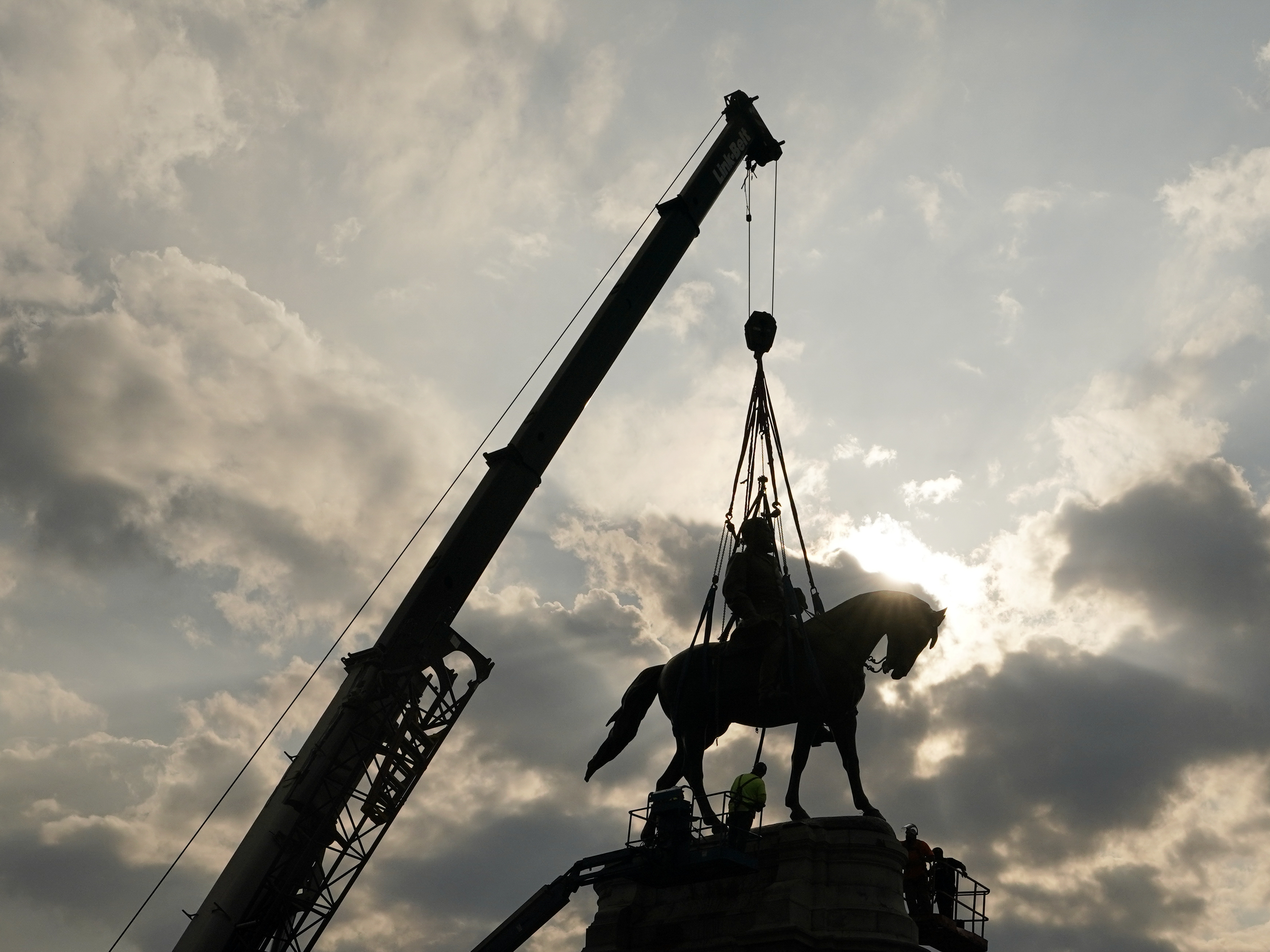 caption: Crews work to remove one of the country's largest remaining monuments to the Confederacy, a towering statue of Confederate Gen. Robert E. Lee on Wednesday in Richmond, Va.
