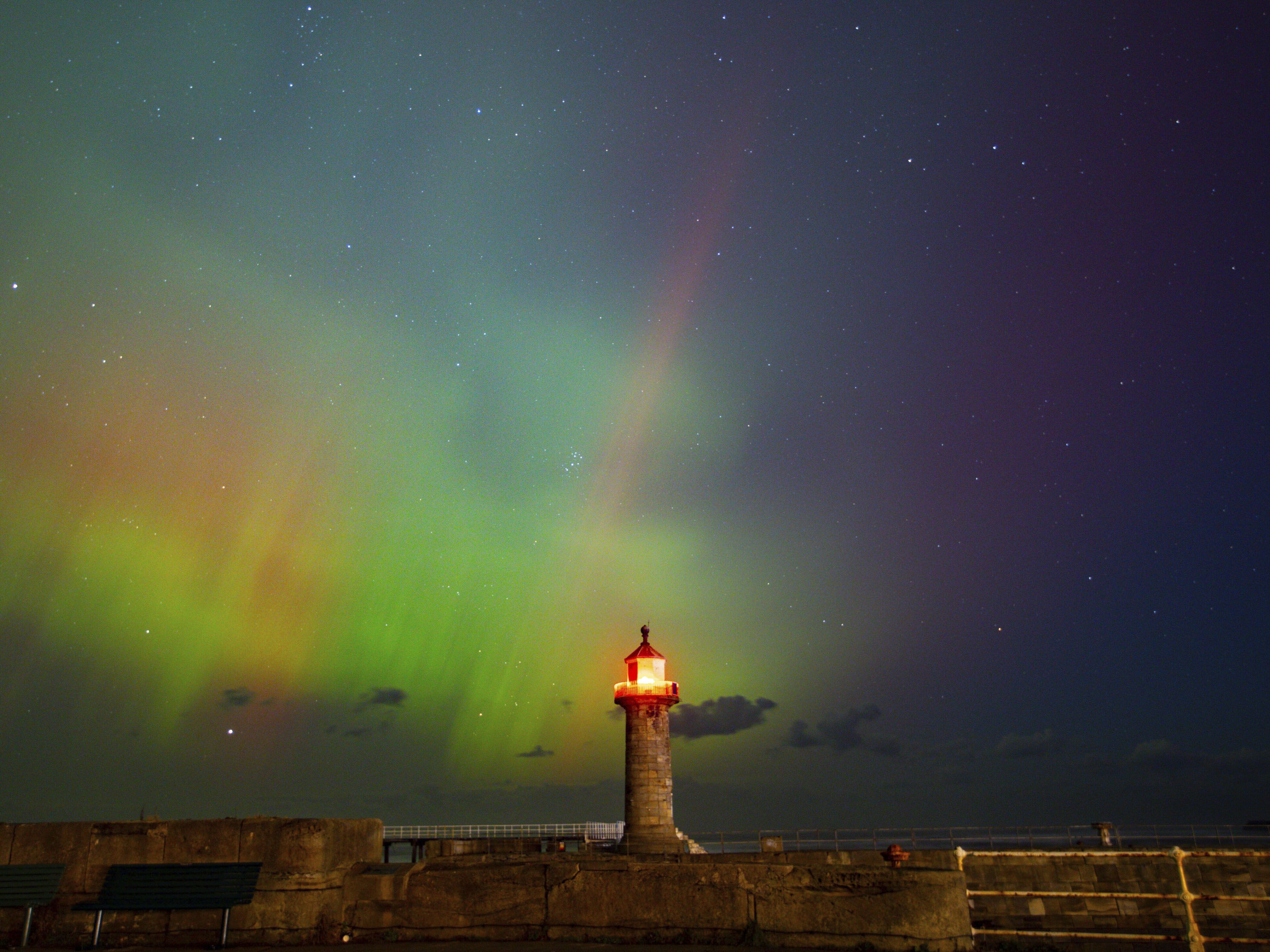 caption: The northern lights, also known as the aurora borealis, are seen in the sky across Whitby Harbour, Whitby, UK, on Oct. 10.
