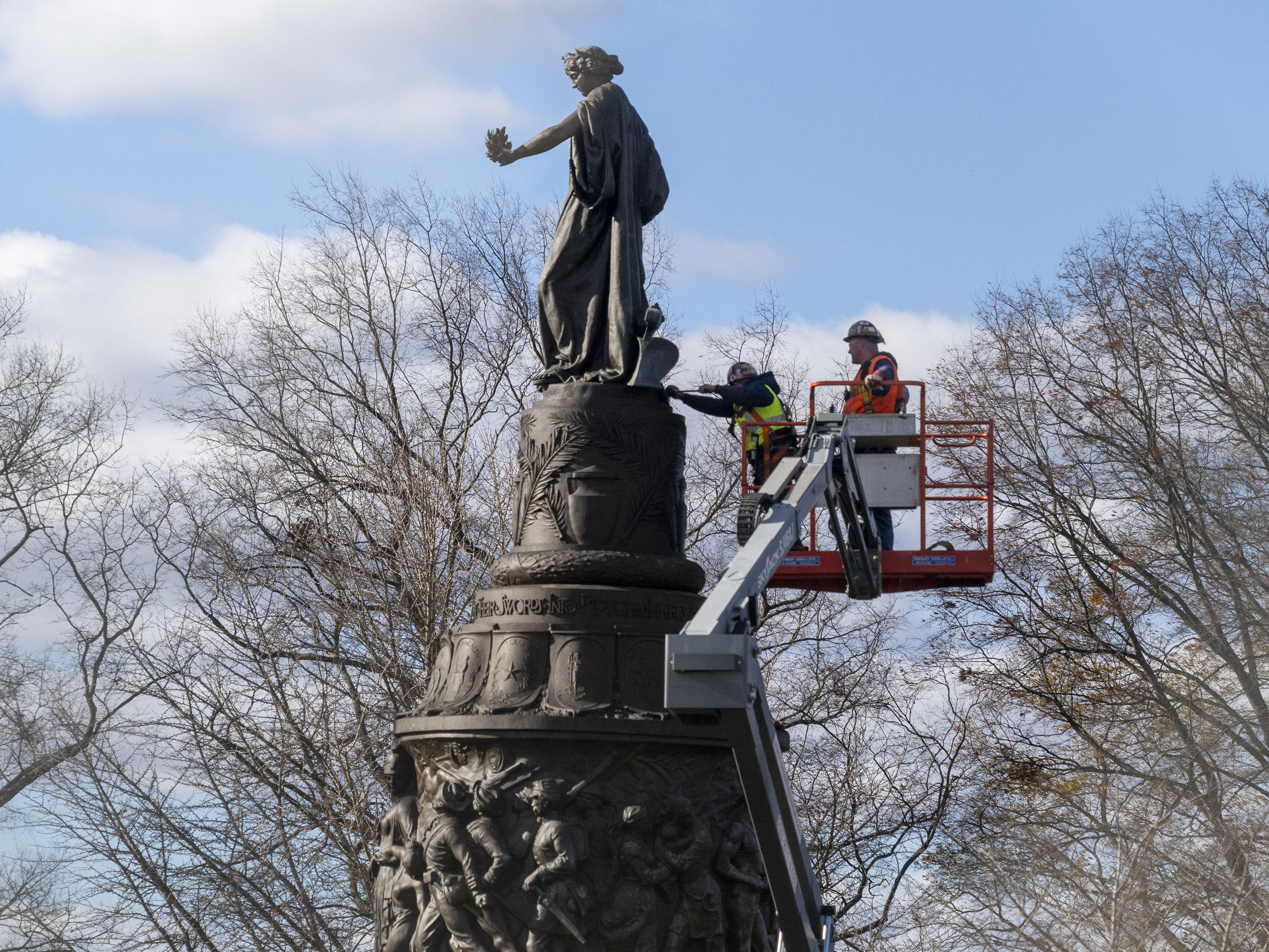 caption: Workers prepare a Confederate memorial for removal in Arlington National Cemetery on Monday.