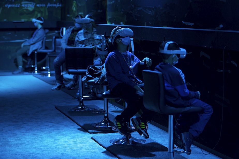 caption: Patrons participate in a virtual reality interactive at the 'Van Gogh: Immersive Experience' exhibit on Wednesday, October 27, 2021, along Occidental Avenue in Seattle.