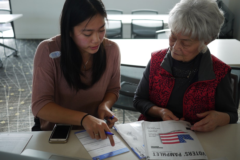 caption: Chinese-American voter Lina Chi (right) gets translation help for her ballot.