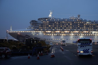 caption: Buses arrive at Yokohama Port, near Tokyo, as the Japan Self-Defense Forces prepare to move American passengers from the quarantined Diamond Princess cruise ship on Sunday.