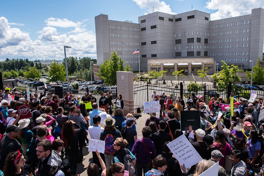 caption: Protesters occupy the sidewalk and into the street during the Solidarity Day protest outside of the Federal Detention Center in SeaTac.