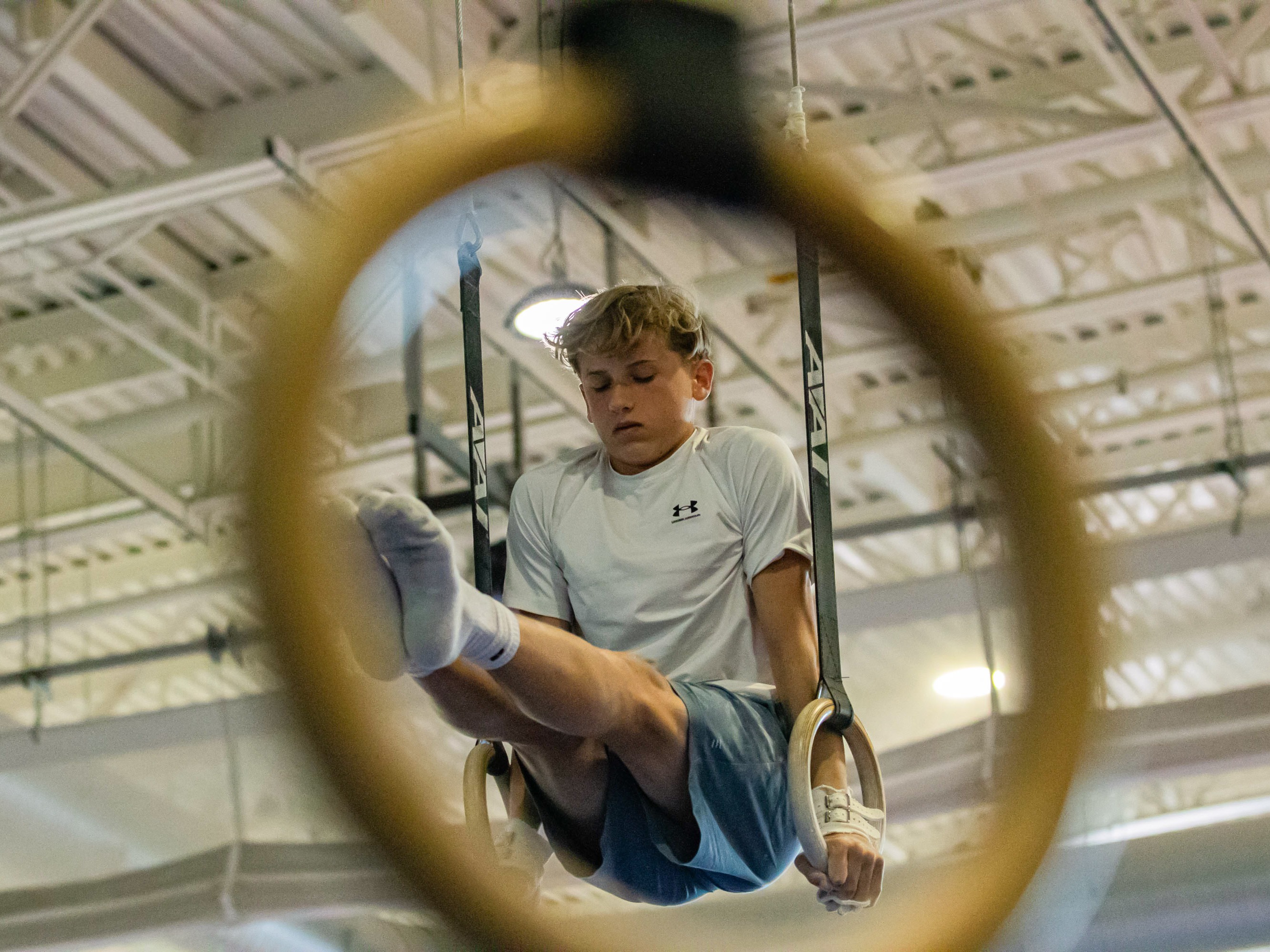 caption: Hobie Biliouris, 14, of the Arlington Tigers gymnastics team practices on the rings at the Barcroft Sports &amp; Fitness Center in Arlington, Va., on July 2. He recently joined the Tigers after his previous team ended its boys program.