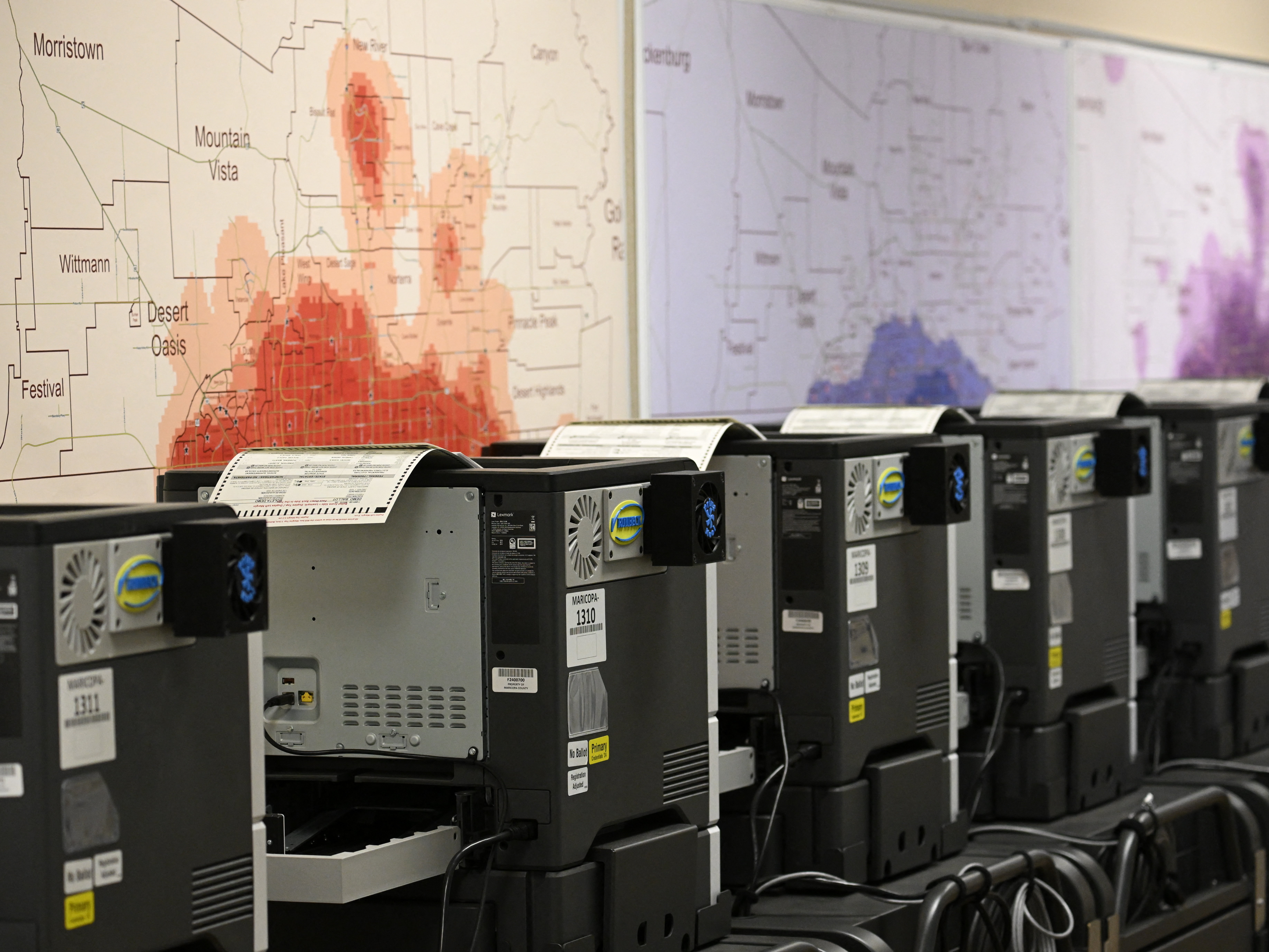 caption: Ballot printers for in-person voting are loaded with test ballots in a storage warehouse at the Maricopa County Tabulation and Election Center in Phoenix on June 3.