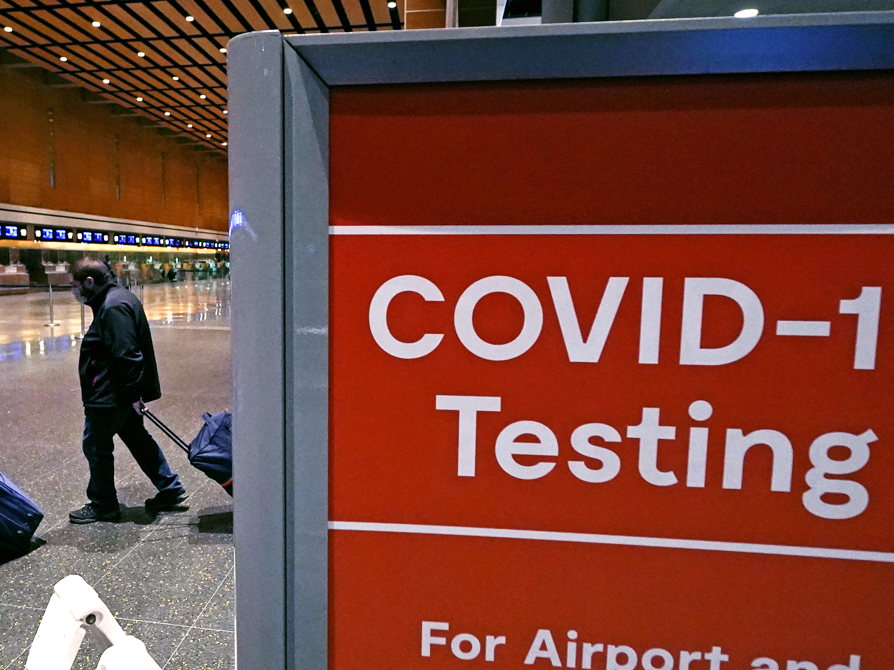 caption: In this file photo, travelers pass a sign for COVID-19 testing at Logan Airport in Boston. The Biden administration is lifting its requirement for COVID testing before flying to the U.S.