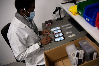 caption: An employee works on smartphones reconditioning in France in January.