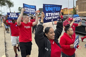 caption: United Auto Workers members march while holding signs at a union rally held near a Stellantis factory Wednesday, Aug. 23, 2023, in Detroit.