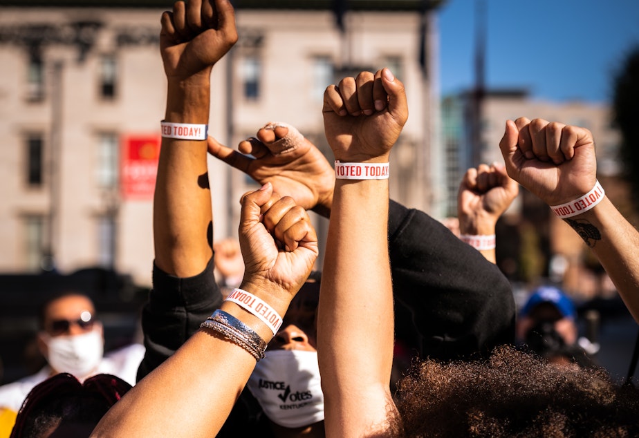 caption: Black Lives Matter protesters display wristbands reading "I VOTED". Activists warn Black and Latino voters are being flooded with disinformation intended to suppress turnout in the election's final days.