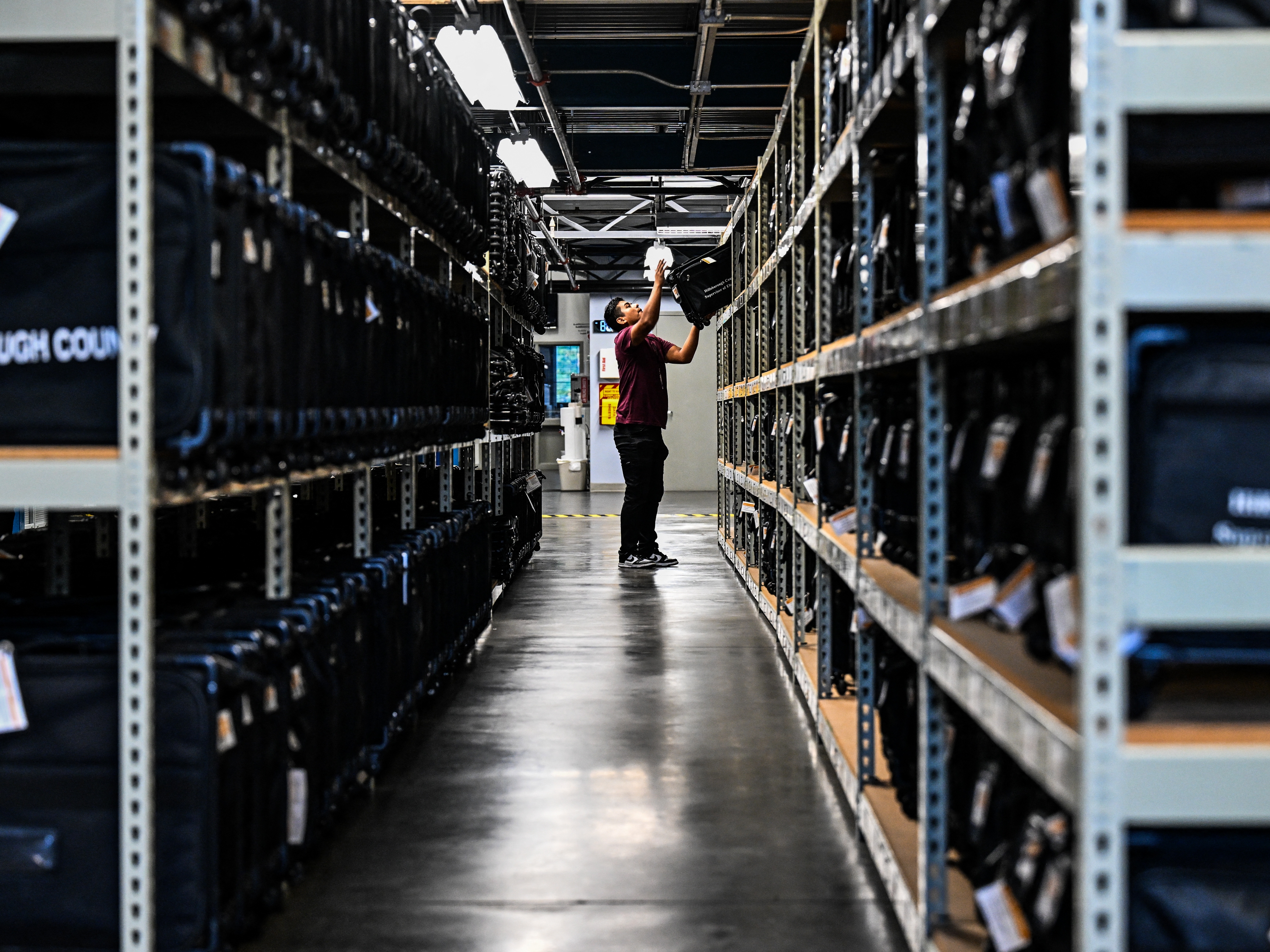 caption: An election office worker moves bags of election supplies at the Robert L. Gilder Elections Service Center in Tampa, Florida, on November 2, 2024.