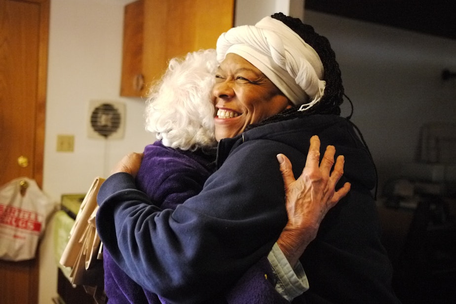 caption: Fai Mathews, a driver for Meals on Wheels, hugs a client at her home in North Seattle. 