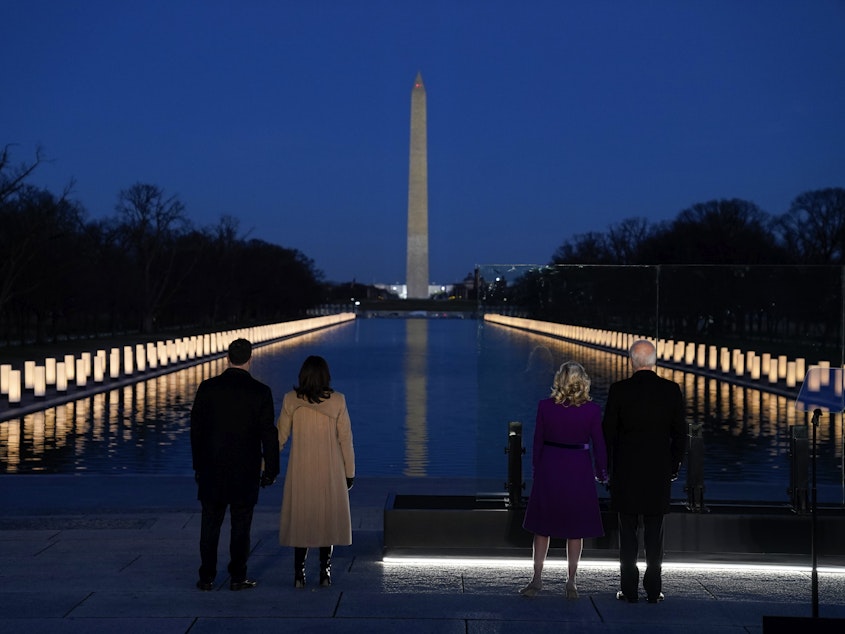caption: President-elect Joe Biden, Jill Biden, Vice President-elect Kamala Harris and Doug Emhoff listen as Yolanda Adams sings "Hallelujah" during a COVID-19 memorial, with lights placed around the Lincoln Memorial Reflecting Pool on Tuesday.