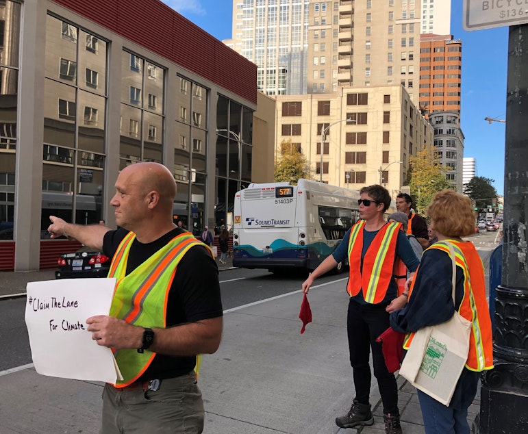 caption: Glen Buhlmann, Meg Wade, and Brie Gyncild of the group 350 Seattle take to the streets on September 26, 2019 to remind car drivers to stay out of the bus lane nearFifth Avenue and Olive Way. 