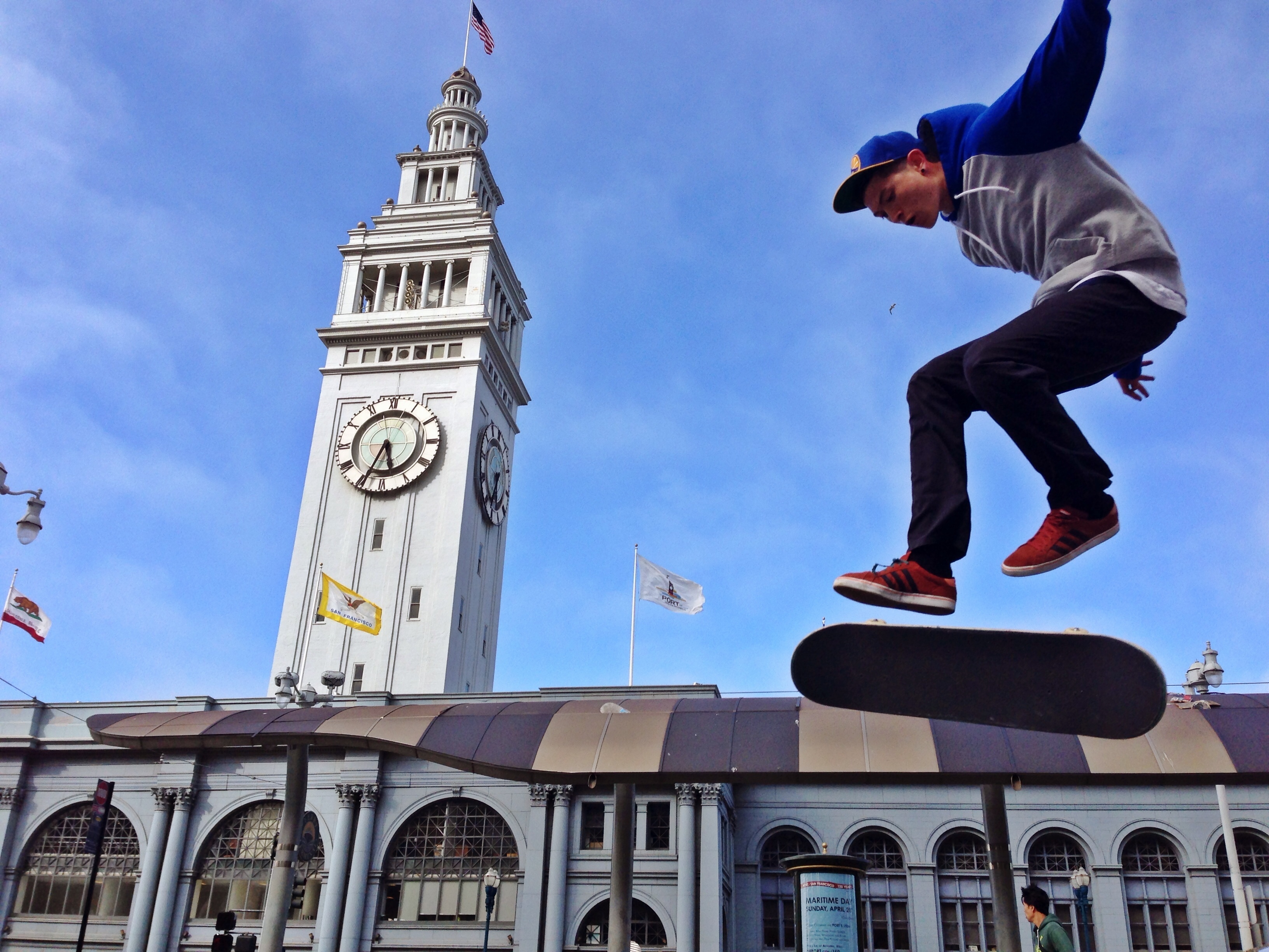caption: A young skateboarder riding in front of the Ferry Building on the Embarcadero in San Francisco California.