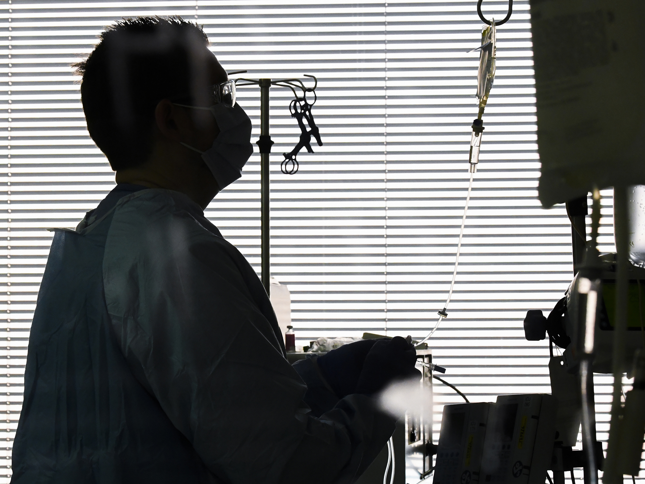 caption: With echoes of the early days of the pandemic, ICU beds are filling to capacity rapidly in several states. In this photo from December 2020, East Alabama Medical Center nurse Harvard Graham checks fluids for a COVID-19 patient in the intensive care unit in Opelika, Ala.