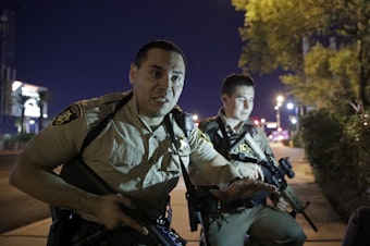 caption: Police officers advise people to take cover near the scene of a shooting near the Mandalay Bay resort and casino on the Las Vegas Strip, Sunday, Oct. 1, 2017, in Las Vegas.