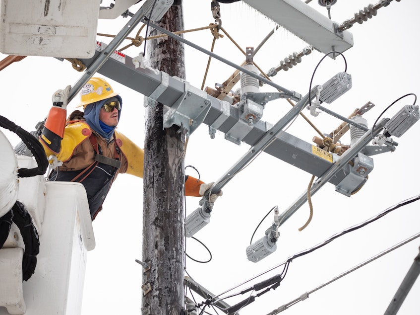 caption: A worker repairs a power line in Austin, Texas, on Thursday. Although power was slowly being restored to much of the state, weather-related water issues persist.