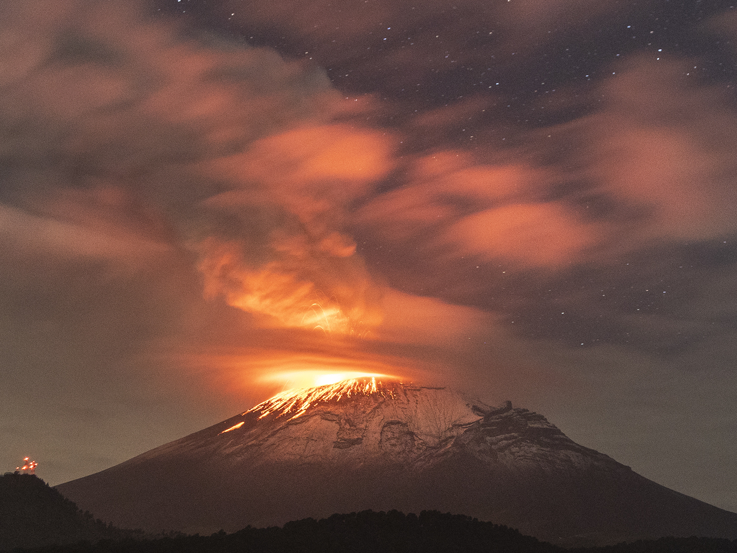 caption: Popocatépetl volcano spews incandescent material on Tuesday. The second highest volcano in the Mexico increased its activity, and authorities raised the alert to the second-highest level.