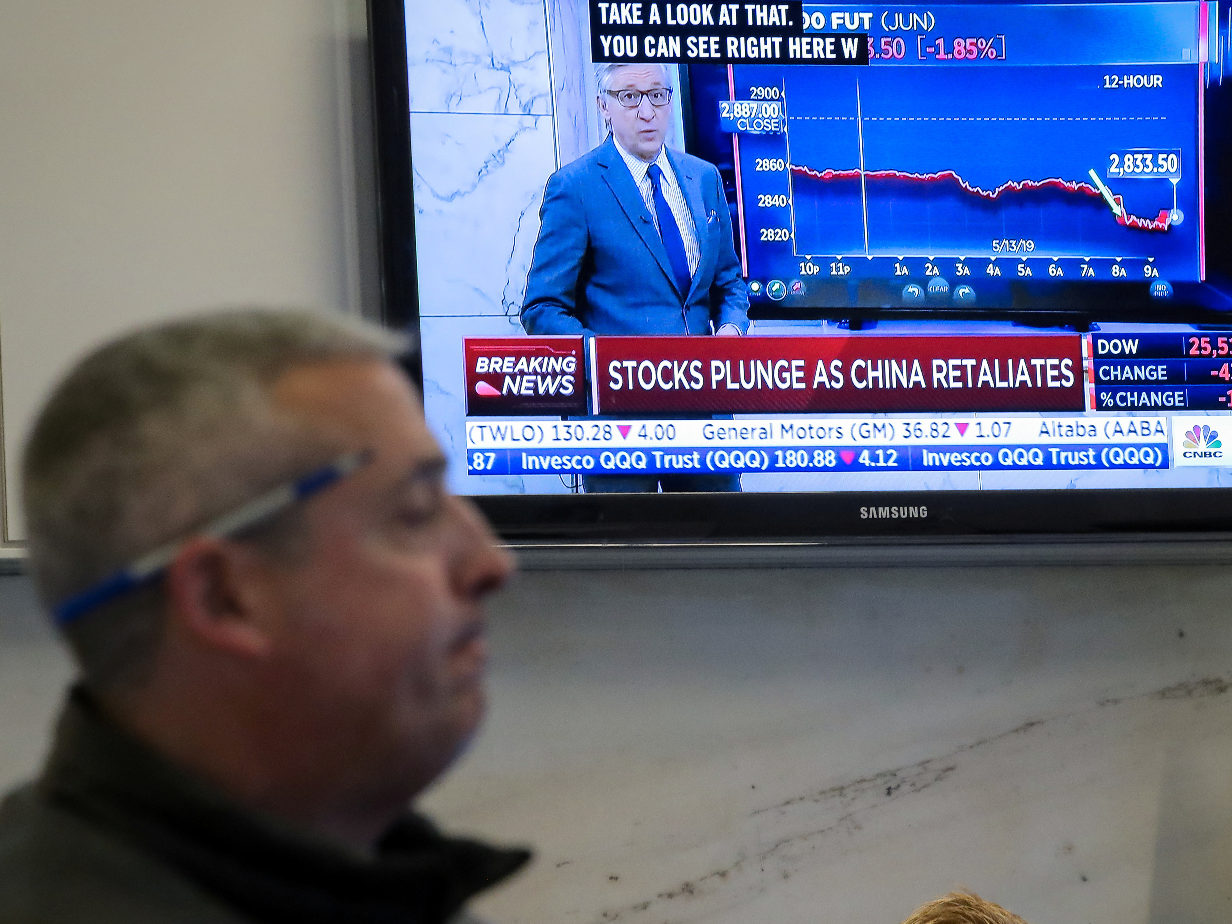 caption: U.S. stocks fell sharply Monday after China retaliated for President Trump's latest round of tariffs. Here, a trader works on the floor at the New York Stock Exchange as a TV shows the state of the market.