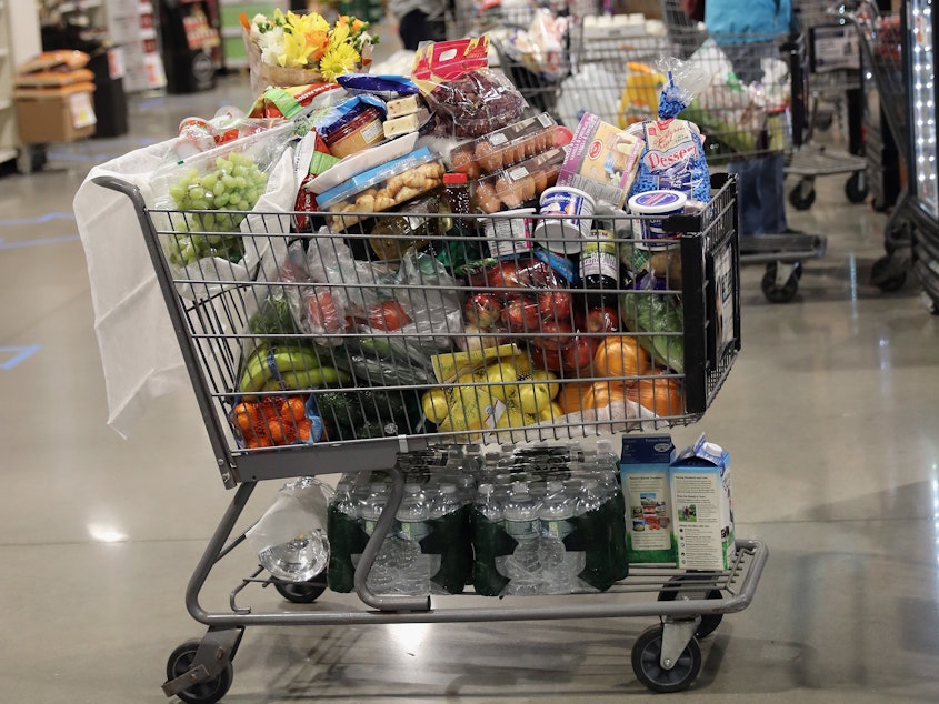 caption: A shopper's full cart is placed on the checkout line at the ShopRite supermarket on April 3, 2020 in Plainview, N.Y. A year later, prices for most goods have jumped, according to government data on Wednesday, as companies struggle to secure critical raw materials amid supply constraints.