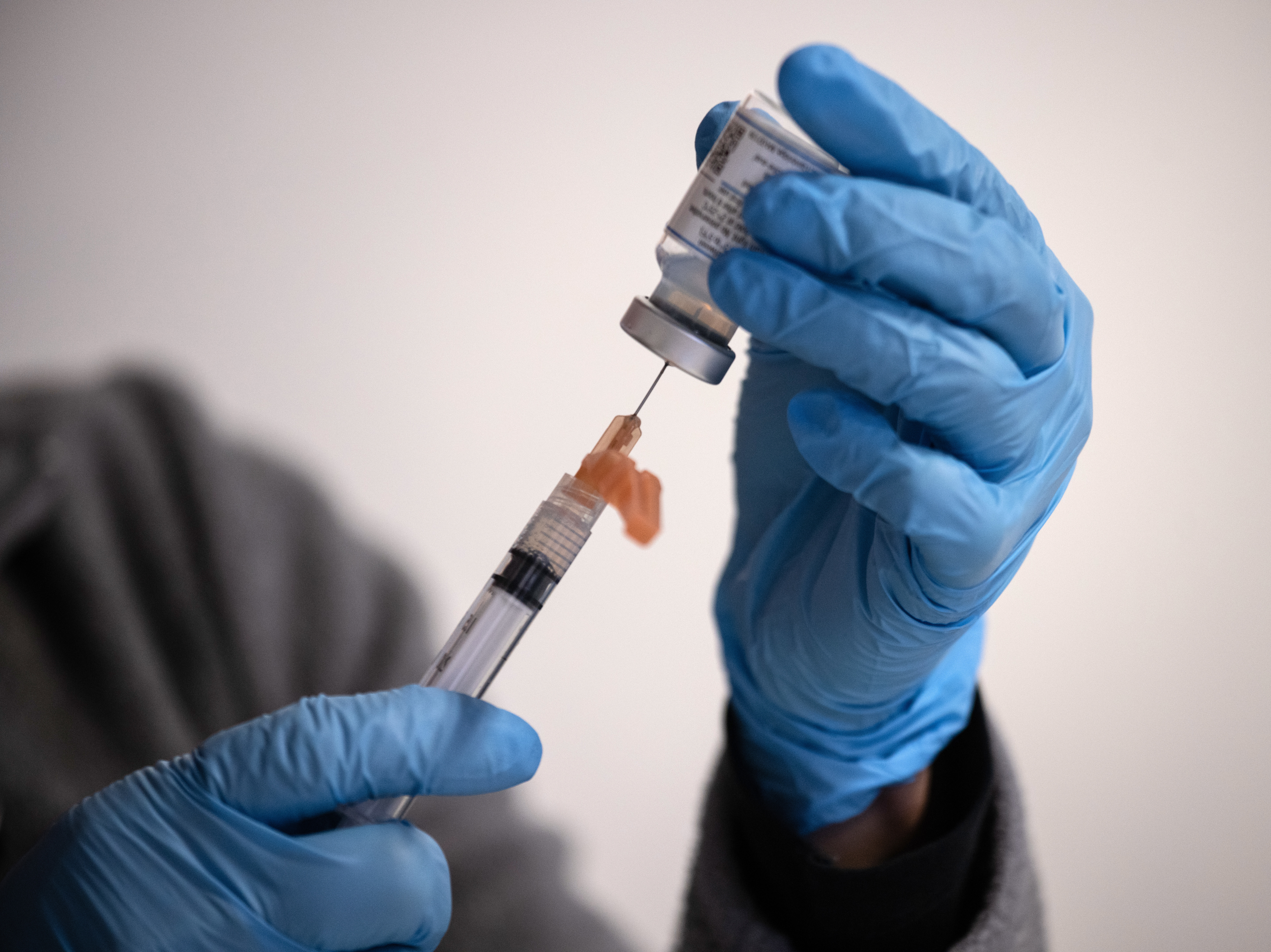 caption: Nurse manager Lucy Golding draws up doses of the Moderna COVID-19 vaccine March 14 in Stamford, Conn. Moderna has begun enrolling infants and young children into a vaccine trial.