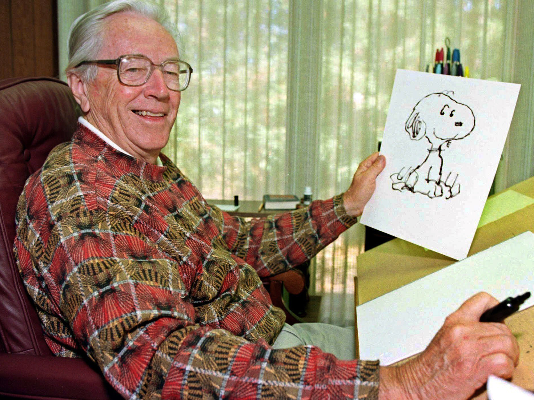 caption: Cartoonist Charles Schulz poses with a sketch of Snoopy in his office in Santa Rosa, Calif. Schulz, who died shortly after his retirement in 2000, would have turned 100 on Nov. 26.