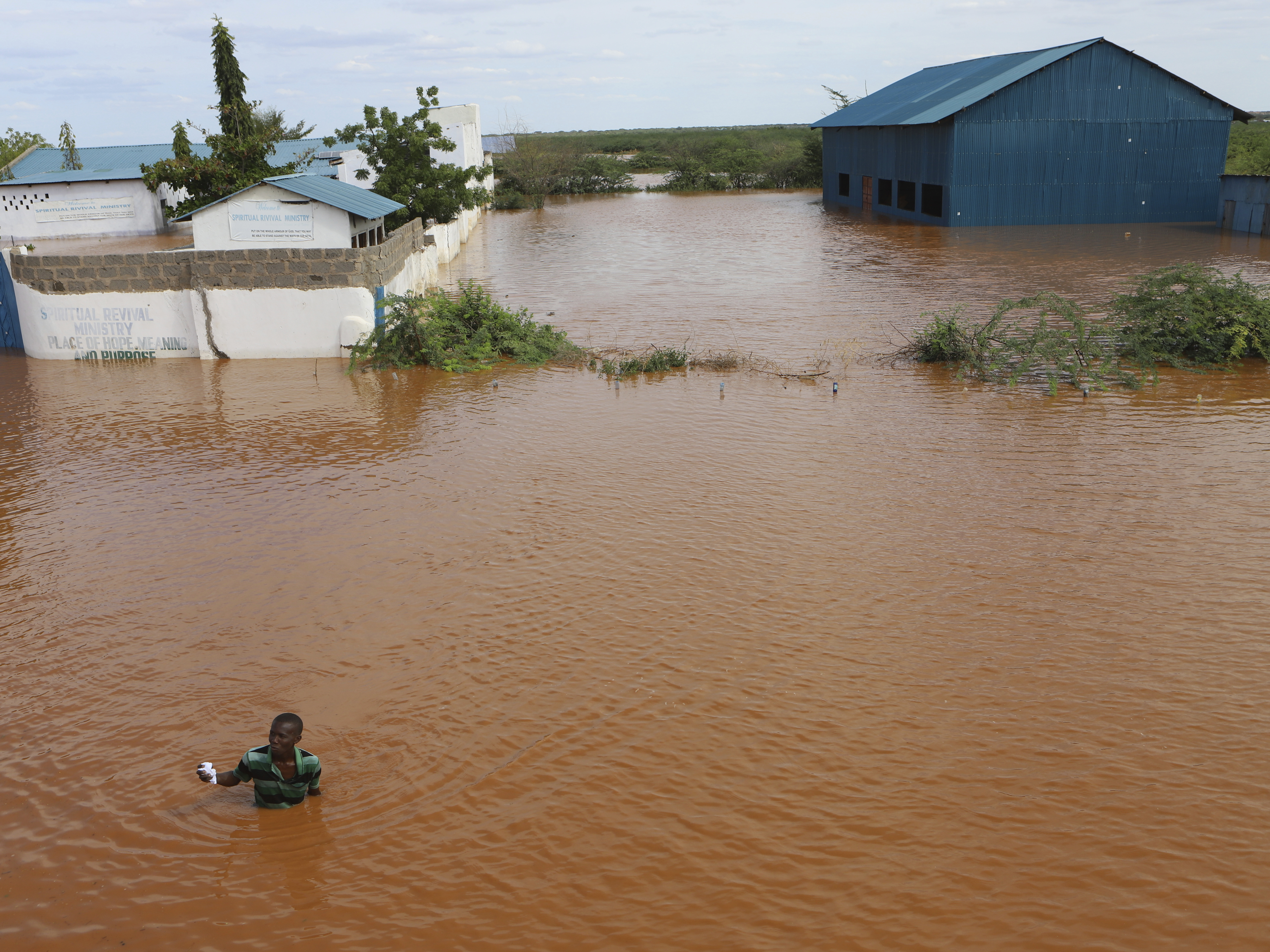 caption: A man swims from a submerged church compound, after the River Tana broke its banks following heavy rains at Mororo, border of Tana River and Garissa counties, northeastern Kenya, April 28. Heavy rains pounding different parts of Kenya have led to dozens of deaths and the displacement of tens of thousands of people, according to the United Nations.