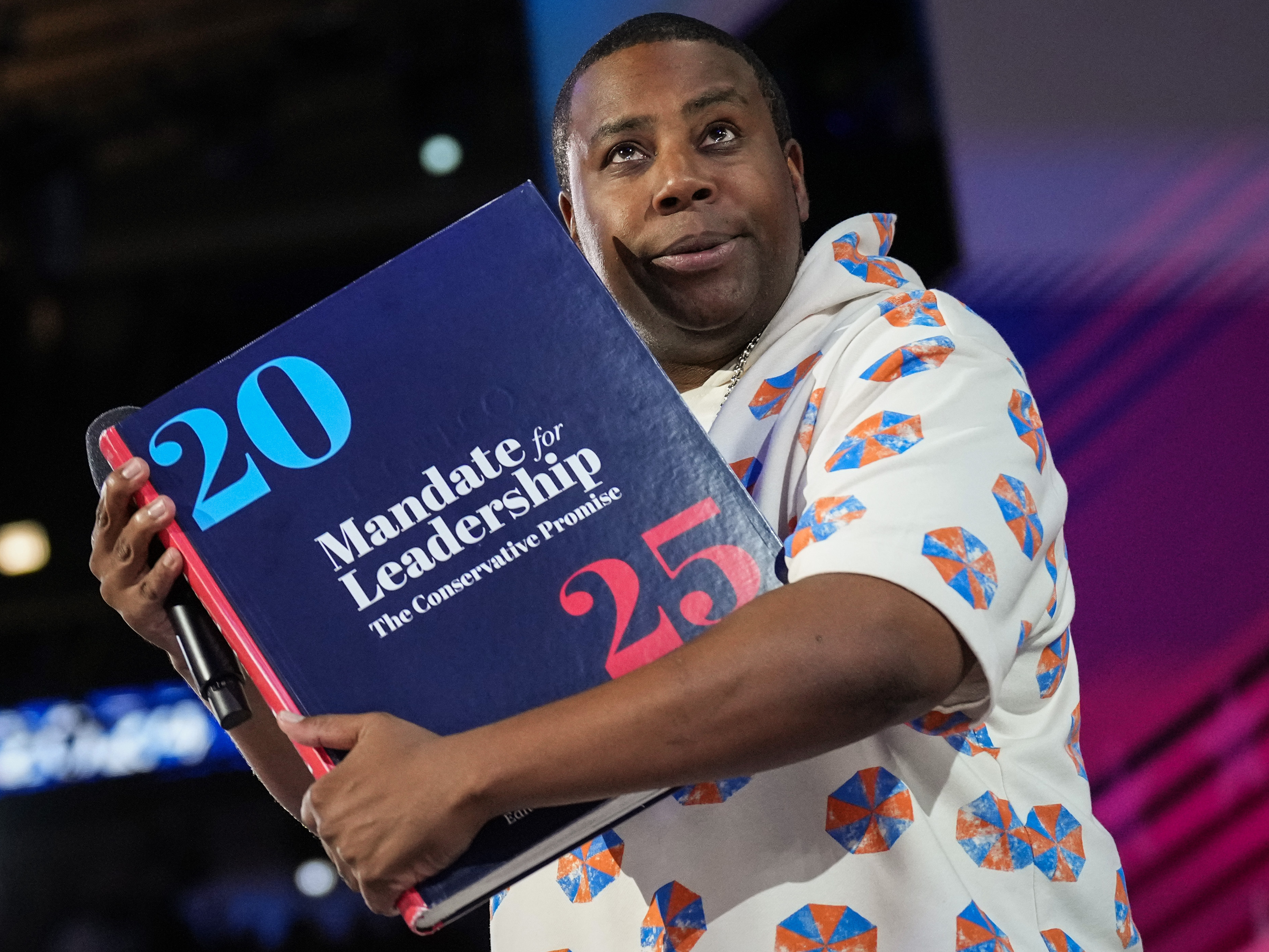 caption: Comedian and actor Kenan Thompson speaks about Project 2025 on stage during the third day of the Democratic National Convention at the United Center on August 21, 2024 in Chicago.