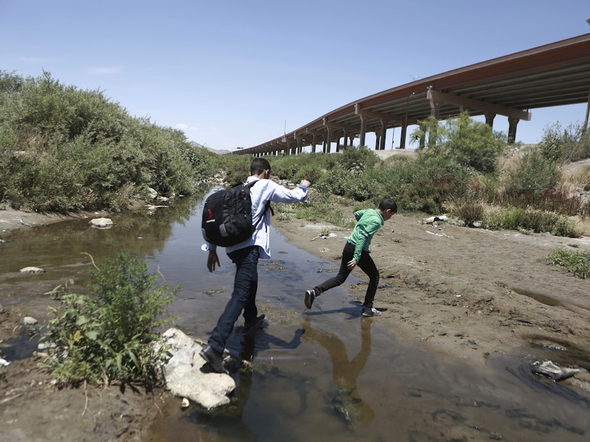 caption: Migrants cross the Rio Grande into the United States, to turn themselves over to authorities and ask for asylum, in Ciudad, Juarez, in June.