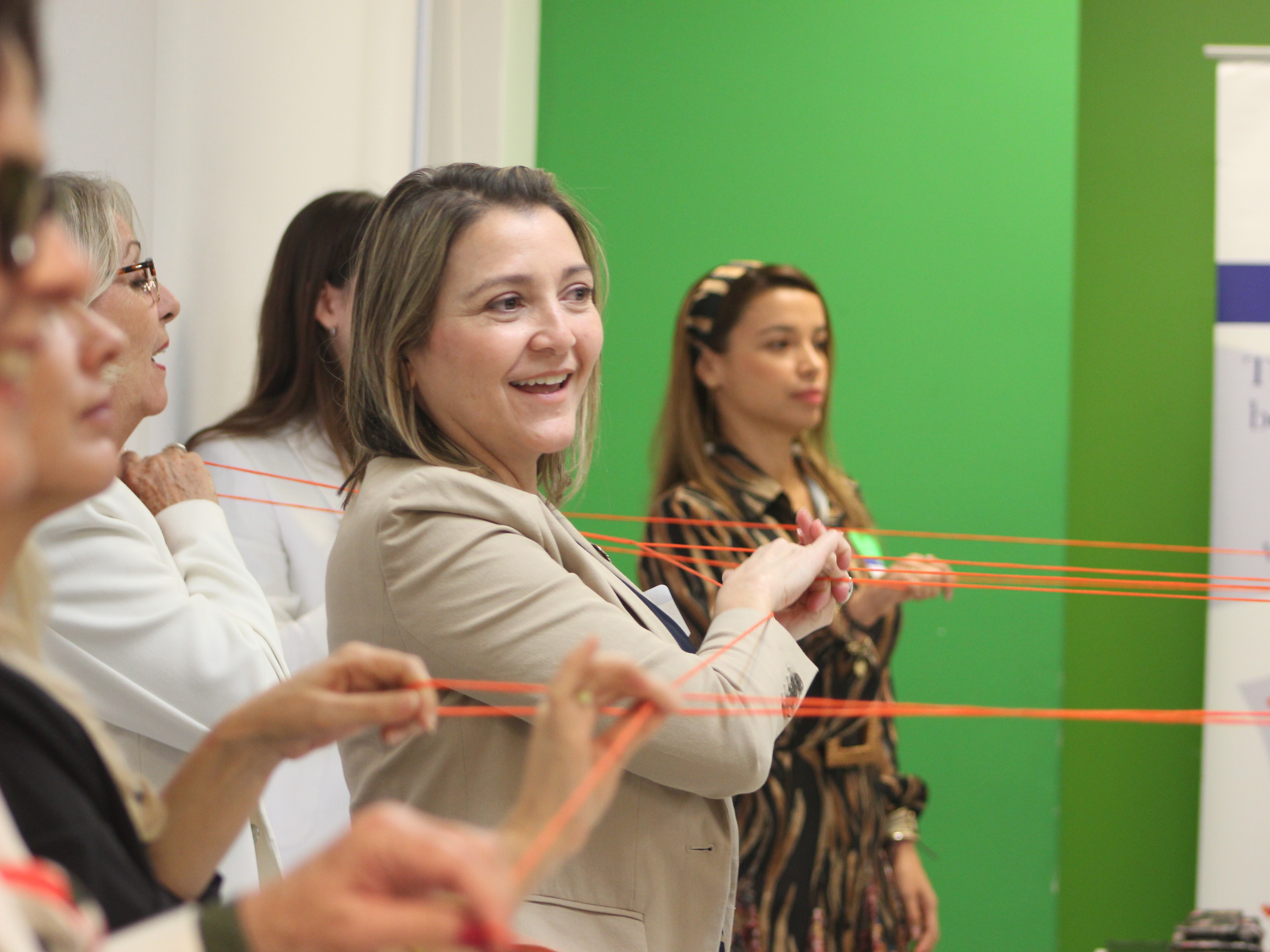 caption: Scarlett Lanzas, second from right, and other information navigators do an exercise in which they use orange string to symbolize how communities are interconnected, at a Nov. 8, 2023, orientation for a pilot project on combating bad information.