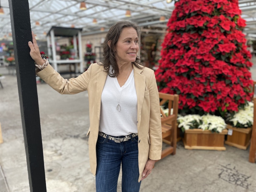 caption: Molbak's CEO Julie Kouhia stands in front of the garden store's poinsettia tree, a hallmark of the store's holiday decorations. After a rift with a developer, the garden and home store opted to close up shop in January 2024. 