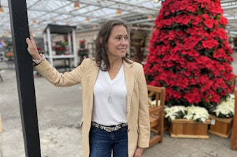 caption: Molbak's CEO Julie Kouhia stands in front of the garden store's poinsettia tree, a hallmark of the store's holiday decorations.