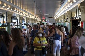 caption: Crowds of people make their way through Pike Place Market on Wednesday, August 11, 2021, in Seattle.