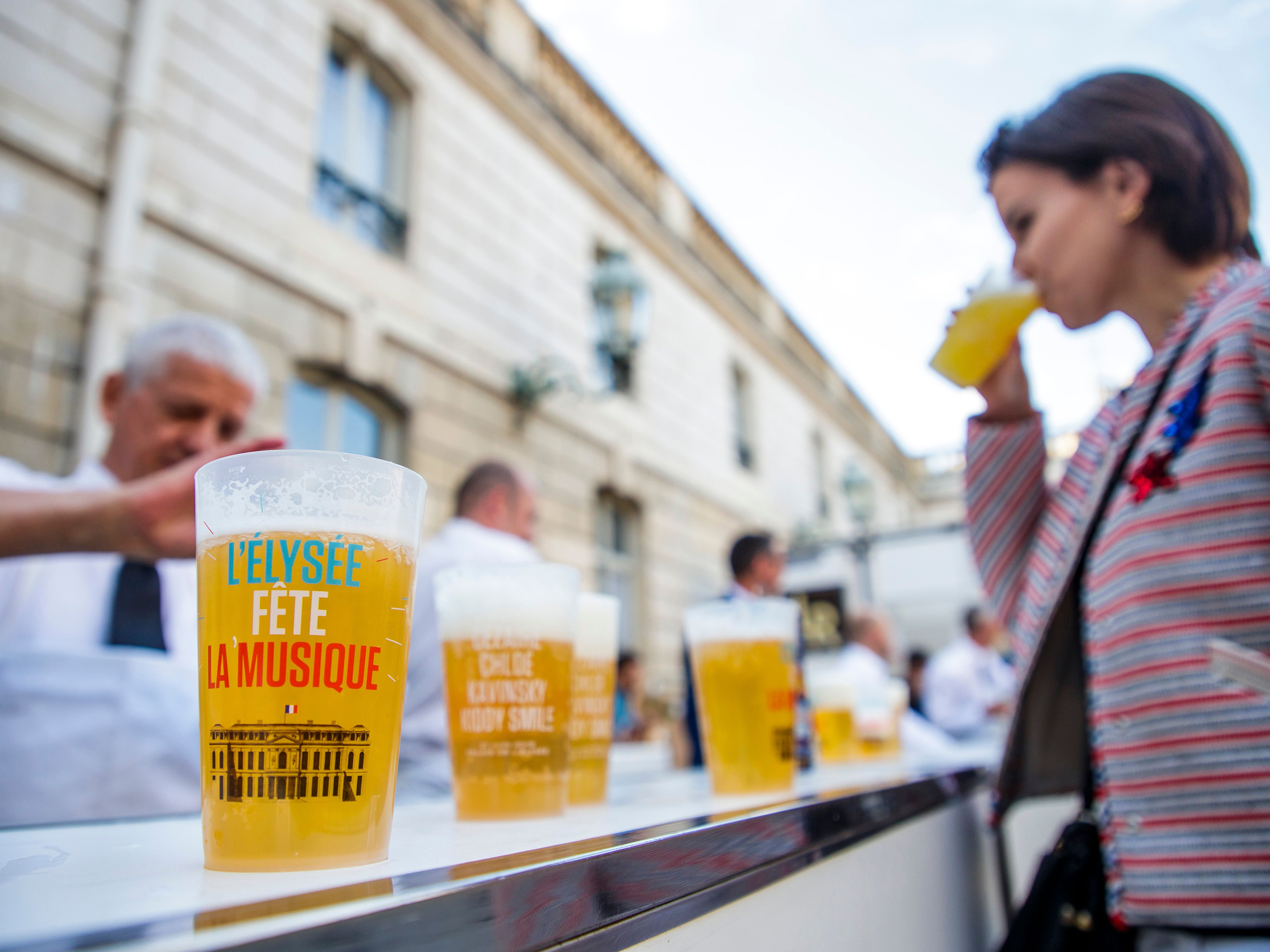 caption: A woman drinks an alcohol-free beer during the annual "Fete de la Musique" (music day), in the courtyard of the Elysee Palace in Paris in 2018.