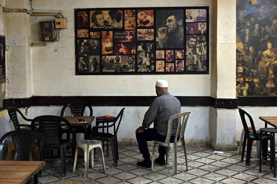 caption: A man prays in coffee shop in Ramallah as news plays in distance bearing ominous news from Gaza on Oct. 31, 2023.