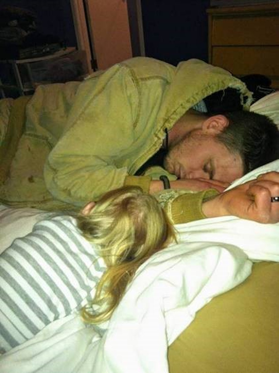 caption: Jeremy Lavender asleep with his daughter in 2011. 